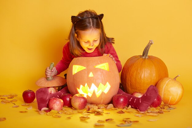 Indoor shot of little cute baby sitting isolated over yellow studio