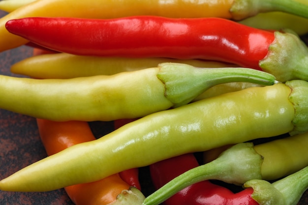 Indoor variety multicolored hot bitter pepper on a brown clay plate close-up macro photography