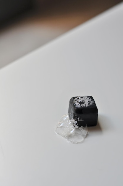 Indoor wet black handmade soap bar with foam and bubbles over white background