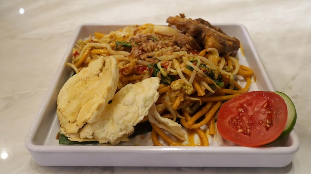 Indulge in oxtail fried noodle served with crunchy crackers and garnished with fresh cucumber and tomato slices