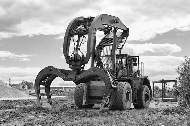 Indusrtial dual function grapple skidder stands on the ground outdoors