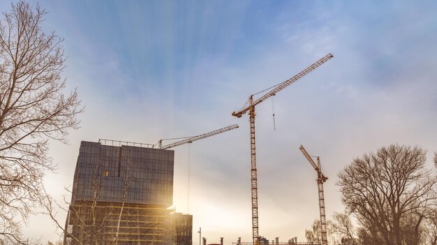 Industrial area with two cranes and an unfinished office building at sunrise