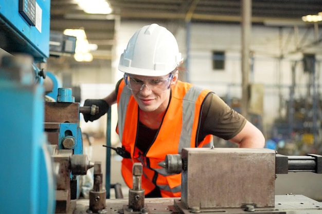 Sfondo industriale di un ingegnere meccanico caucasico che opera una macchina da tornio per la lavorazione dei metalli in una fabbrica di lavorazione dei metalli