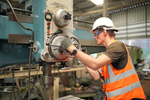 Sfondo industriale di un ingegnere meccanico caucasico che opera una macchina da tornio per la lavorazione dei metalli in una fabbrica di lavorazione dei metalli