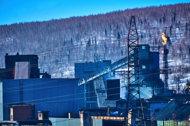 産業の背景-コークス化学プラントのトーチは、冬の風景を背景に大気中に熱を放出します