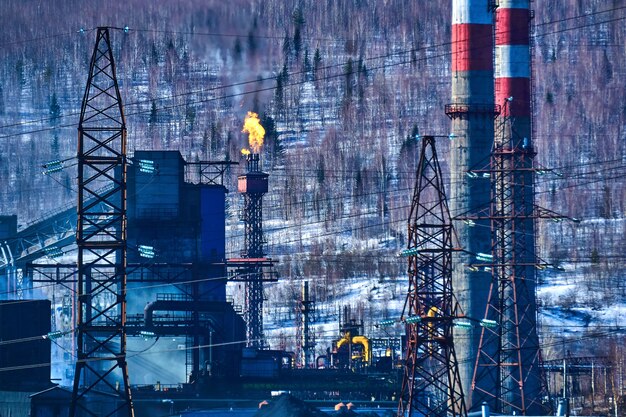 Industrial background - the torch of a coke-chemical plant produces thermal emissions into the atmosphere against the background of a winter landscape