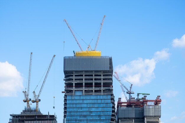 Foto grandi gru industriali che lavorano in cantiere per costruire moderni edifici alti alla luce del giorno