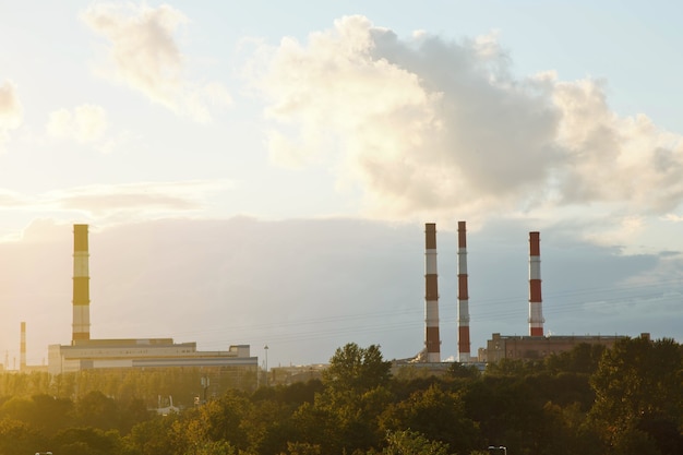 テクスチャード加工の夕焼け空を背景にした工業用レンガの煙突。都市における生産と環境汚染の概念。サイトの著作権スペース