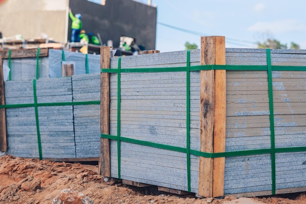 Industrial building cement pressed materials Concrete block cement brick Finished products on pallets compactly stacked wooden frame placed on construction site house rope tape packed open air sky