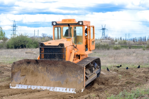 Industrial building construction site bulldozer leveling and moving soil during highway building. Yellow bulldozer at a loamy construction site