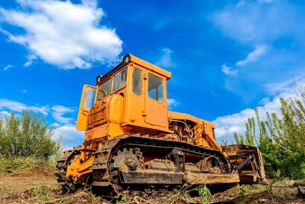 Industrial building construction site bulldozer leveling and moving soil during highway building. Yellow bulldozer at a loamy construction site