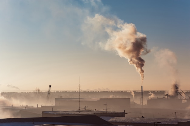 Фото Промышленные здания в тумане на голубом небе. складские помещения. дым из трубы.