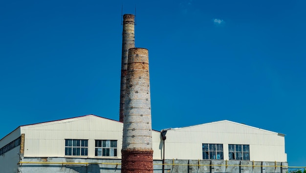 Industrial chimneys of the enterprise against the blue sky