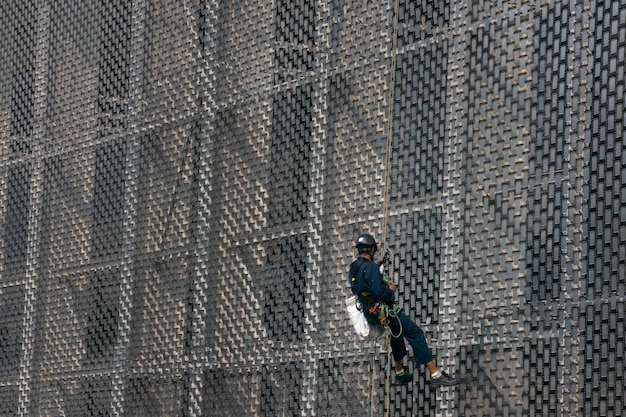 ロープの産業用クライマー労働者が吊り下げ構造の建物をきれいに作業