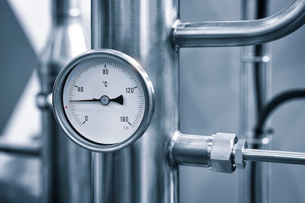 Photo industrial concept equipment of the boilerhouse valves tubes pressure gauges thermometer close up of manometer pipe flow meter water pumps and valves of heating system in a boiler room