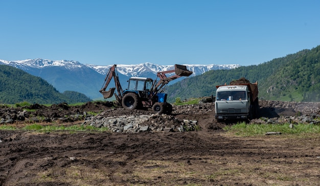 Industrial excavator loading soil from sandpit into a dumper truck