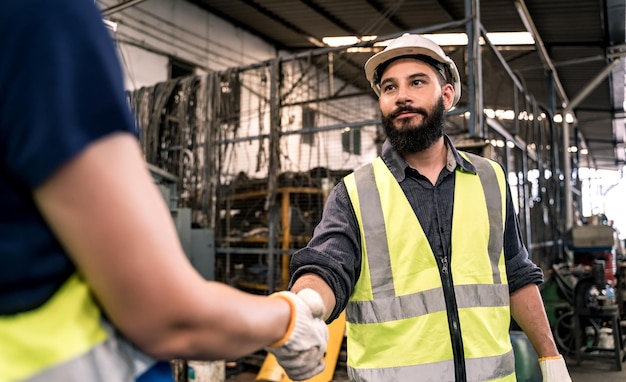 Concetto di fabbrica industriale. stretta di mano ingegneristica con tecnico e operaio addetto alla manutenzione e alla manutenzione dei macchinari.