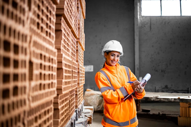 industrial female worker checking inventory of bricks ready to deliver to the construction site