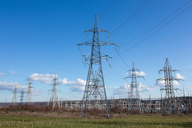 Industrial landscape. High voltage towers with electrical wires on blue sky.