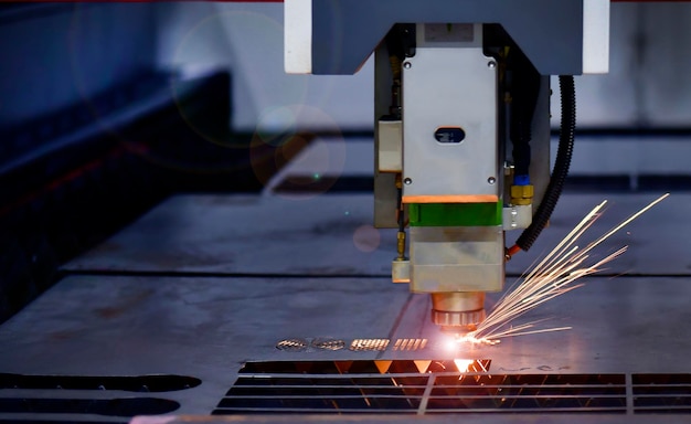 Foto macchina taglio laser industriale durante il taglio della lamiera con la luce scintillante