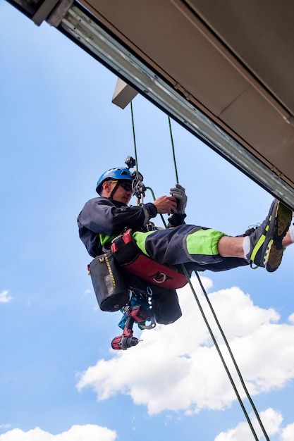 Industrial mountaineering worker hangs over residential\
building while installing