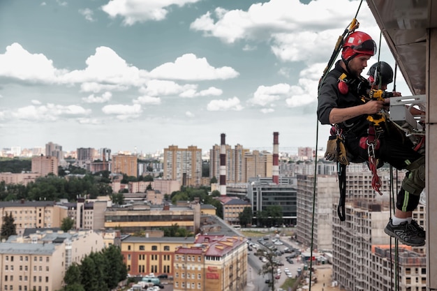 Industrial mountaineering worker hangs over residential\
building while installing