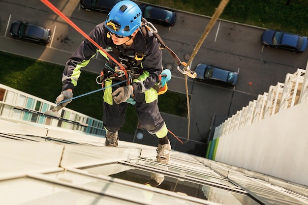 Industrial mountaineering worker hangs over residential facade building