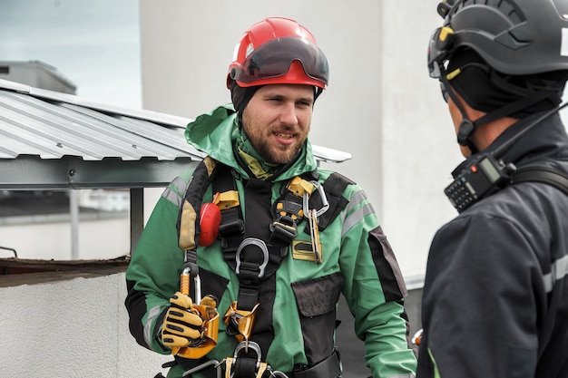 Industrial mountaineering workers in uniform on roof\
residential facade building during high-rise work. rope access\
laborers on roof of house. concept of industry urban works. copy\
space