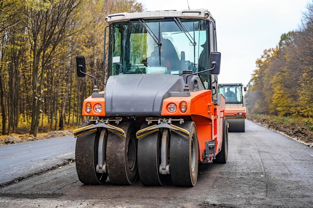 新しい新鮮なアスファルトを敷設する工業用舗装機械。高速道路建設現場の新鮮なアスファルト。