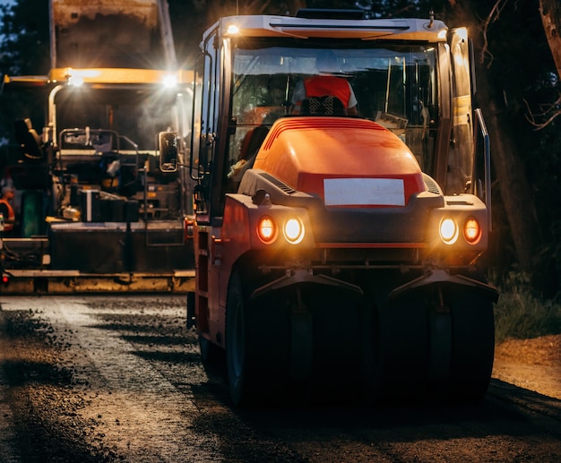 Industrial pavement truck is laying fresh asphalt on\
construction site road service repairs the hig