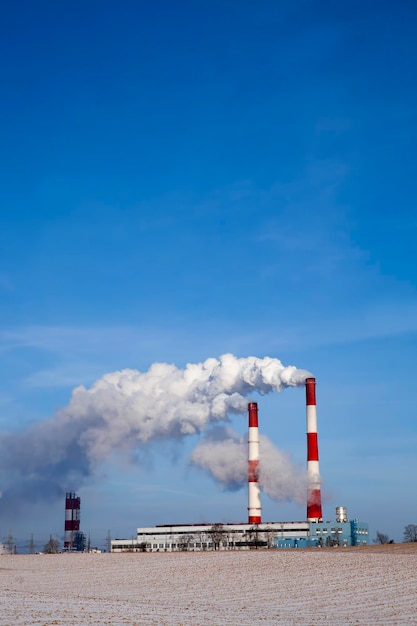 Industrial pipes with white smoke in winter