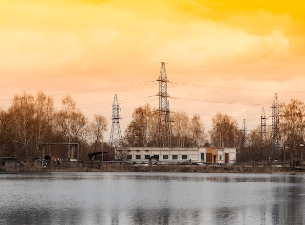 Industrial power lines on sunset river background