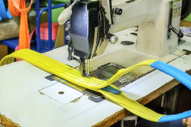 Industrial sewing machine sews a webbing sling. Manufacture of textile slings and tie straps.