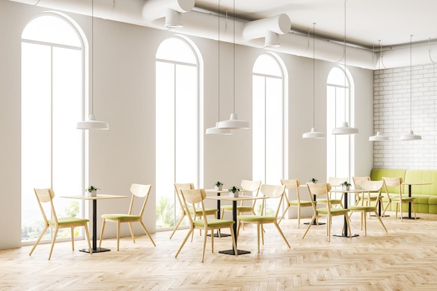 写真 カフェのインテリアは白いレンガの壁木製の床アーチ付きの窓椅子と緑色のソファが付いた木製のテーブルです 3dレンダリングモックアップ
