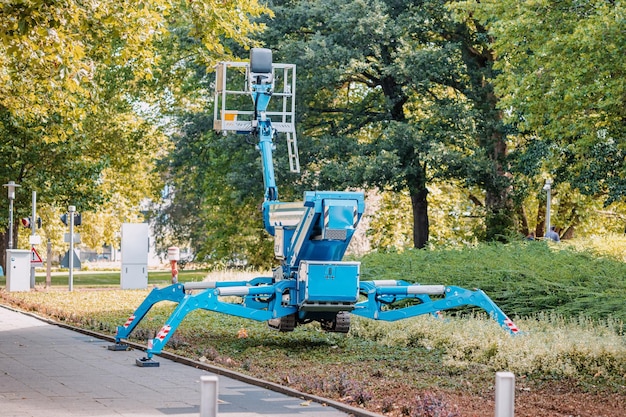 都市公園でクモのように油圧支持脚の上に立つ工業用伸縮式無人クレーン