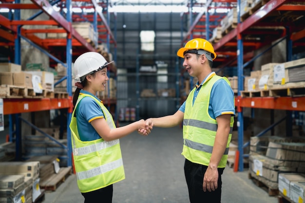 Industrial warehouse asian worker in safety suite handshake\
celebrate successful or deal commitment logistics supply chain and\
warehouse businessteamwork unity under view concept