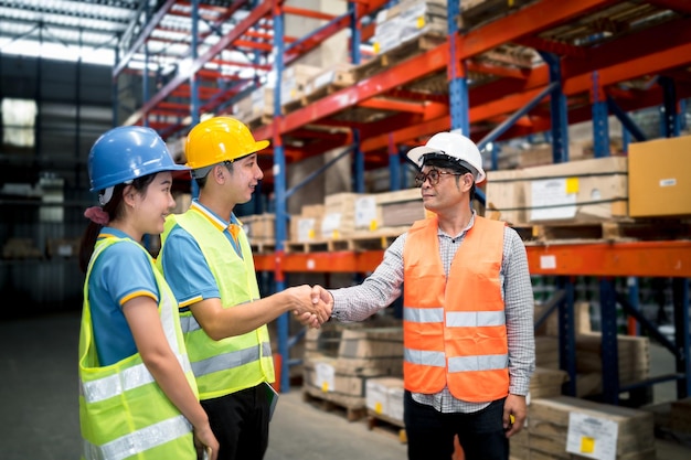 Industrial warehouse asian worker in safety suite handshake\
celebrate successful or deal commitment logistics supply chain and\
warehouse businessteamwork unity under view concept