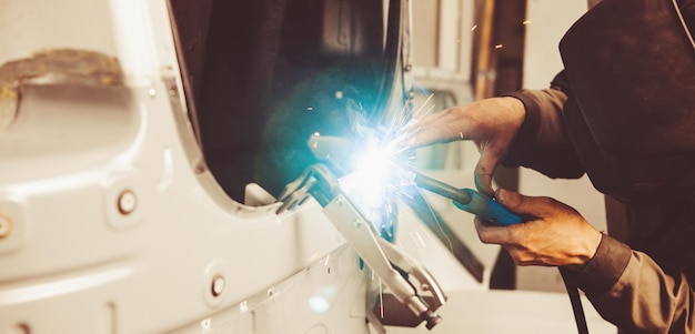 Industrial welder welds back bodywork of car Weld of vehicle