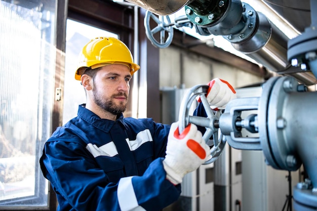 Industrial worker closing valve of gas pipeline inside heating plant