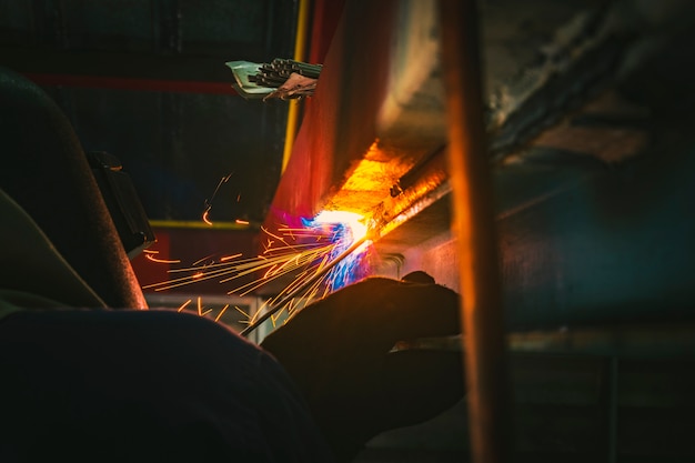 Industrial Worker at the factory welding steel by electric welder