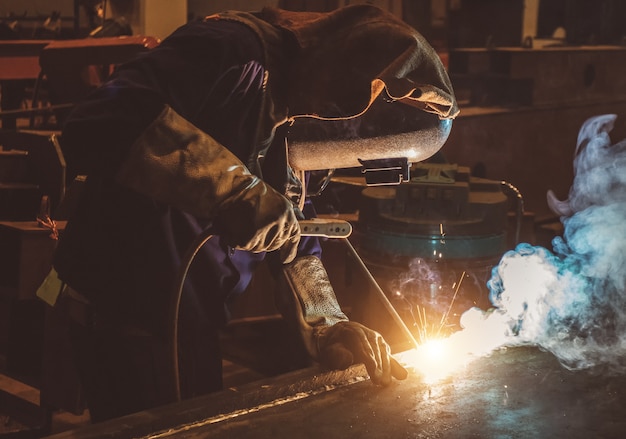 Industrial Worker labourer at the factory welding steel structure