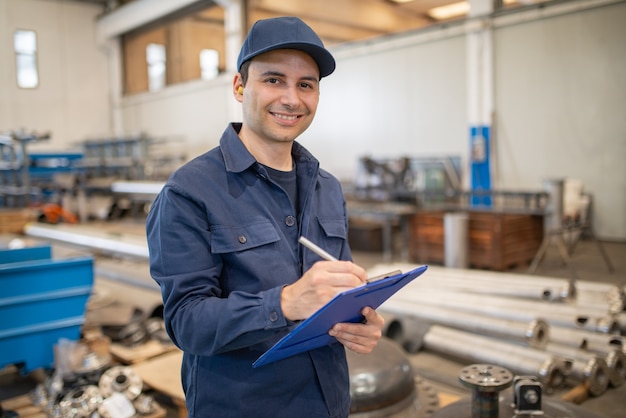 Operaio industriale che scrive su un documento in una fabbrica