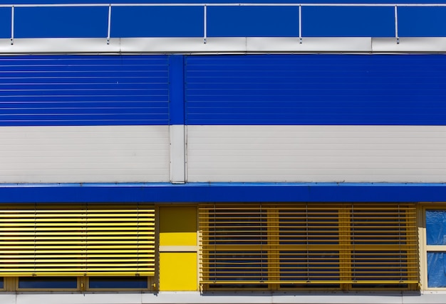 Industrieel gebouw met blauwe en gele metalen gevelbekleding. Abstracte achtergrond.