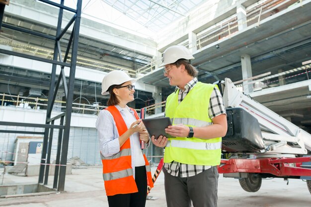 Industrieel portret van mannelijke en vrouwelijke ingenieurs in de bouw van commercieel administratief gebouw