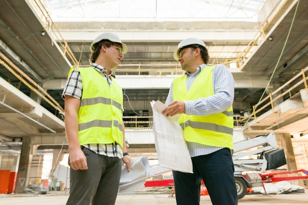 Industrieel portret van twee mannen aan het werk op de bouwplaats. Bouwen, ontwikkelen, industrie en mensenconcept