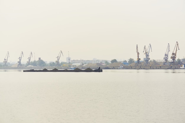 Industrieel rivierwaterlandschap met droog bulkvrachtschip en vrachtterminal in ochtendmist