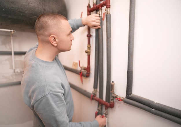 Foto industrieel systeemingenieur pronkt met zijn glimlach terwijl hij het verwarmingssysteem repareert de blanke ingenieur raadt aan om duurzame verwarmingssystemen te gebruiken