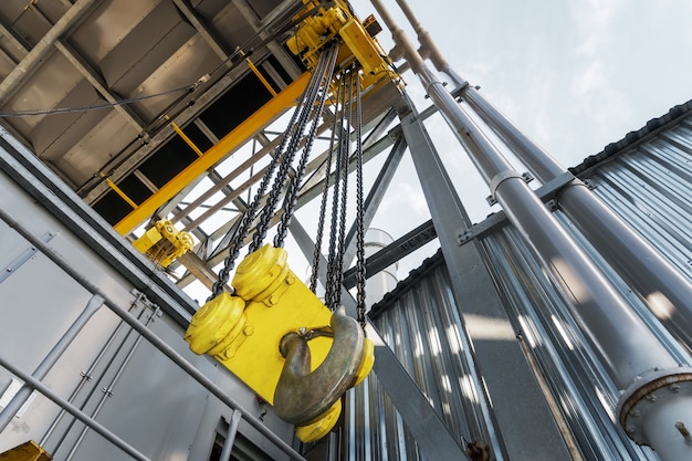 Industriële bovenloopkraan met een ketting en een grote gele haak in de fabriek. hijsmechanisme: