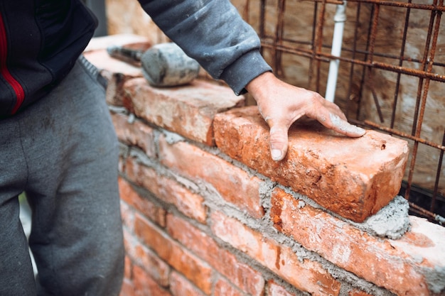 Industriële metselaar bouwvakker die stenen legt en muren bouwt op de bouwplaats Detail van de hand die stenen aanpast en plaatst