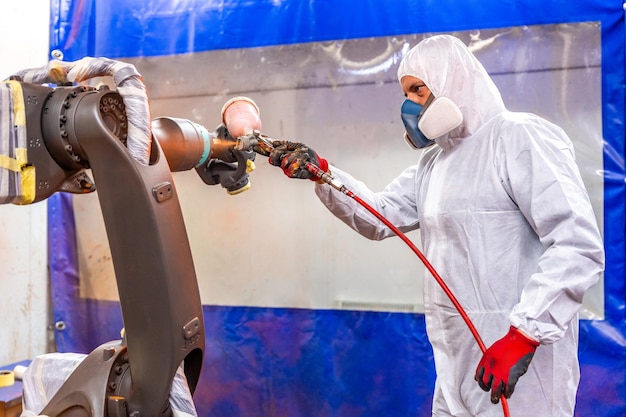 Foto industriële schilder die een spuitpistool gebruikt om een robotarm te schilderen in een industriële robotindustrie